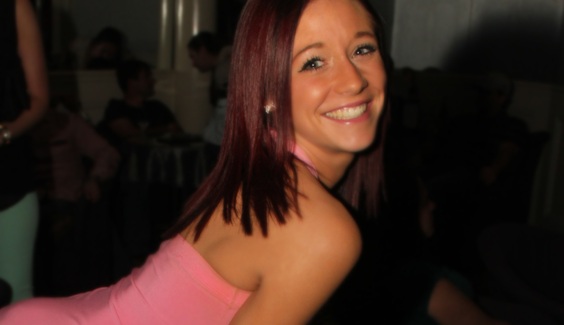 Smiling brunette in a pink shirt at the Baton Rouge strip club image - The Penthouse Club